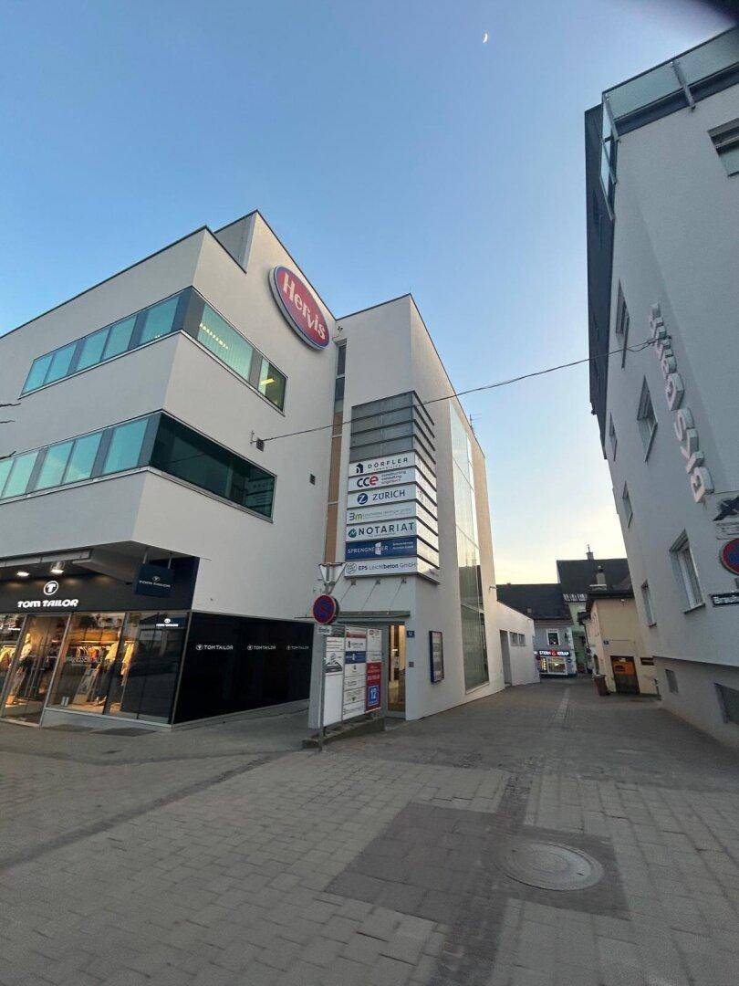Modernes Geschäftsgebäude mit Ladenflächen und Büros, gelegen an einer städtischen Straße.