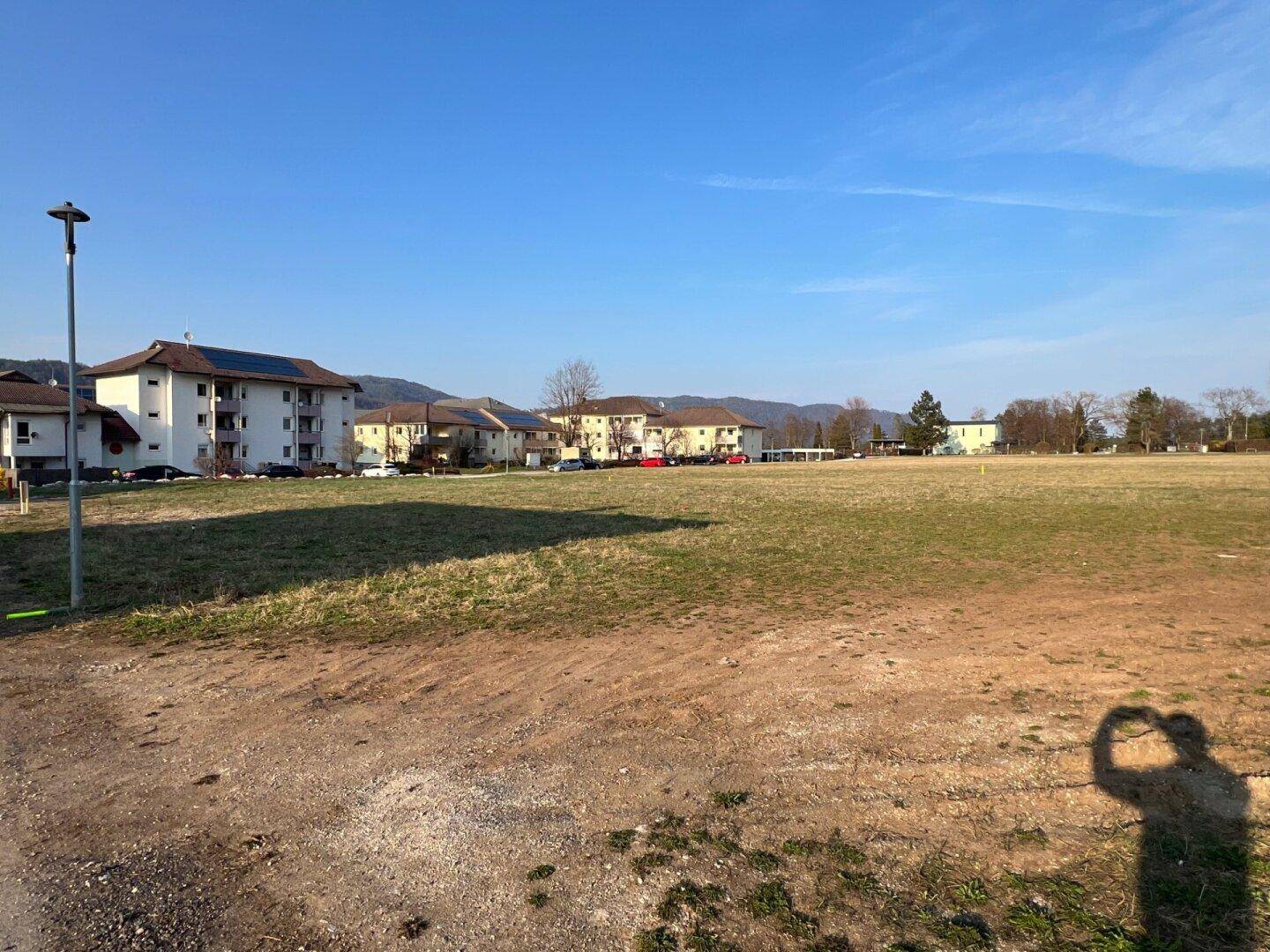 Großes unbebautes Grundstück mit angrenzenden Wohngebäuden und klarer Sicht auf die Umgebung.