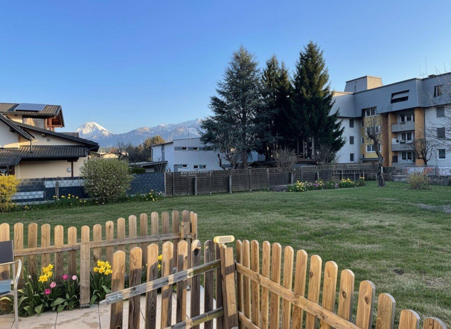 Blick von der Terrasse über den Garten auf die Berge und die umliegende Bebauung.