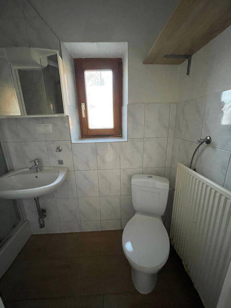 Kleines Badezimmer mit WC, Waschbecken, Spiegelschrank und Fenster.