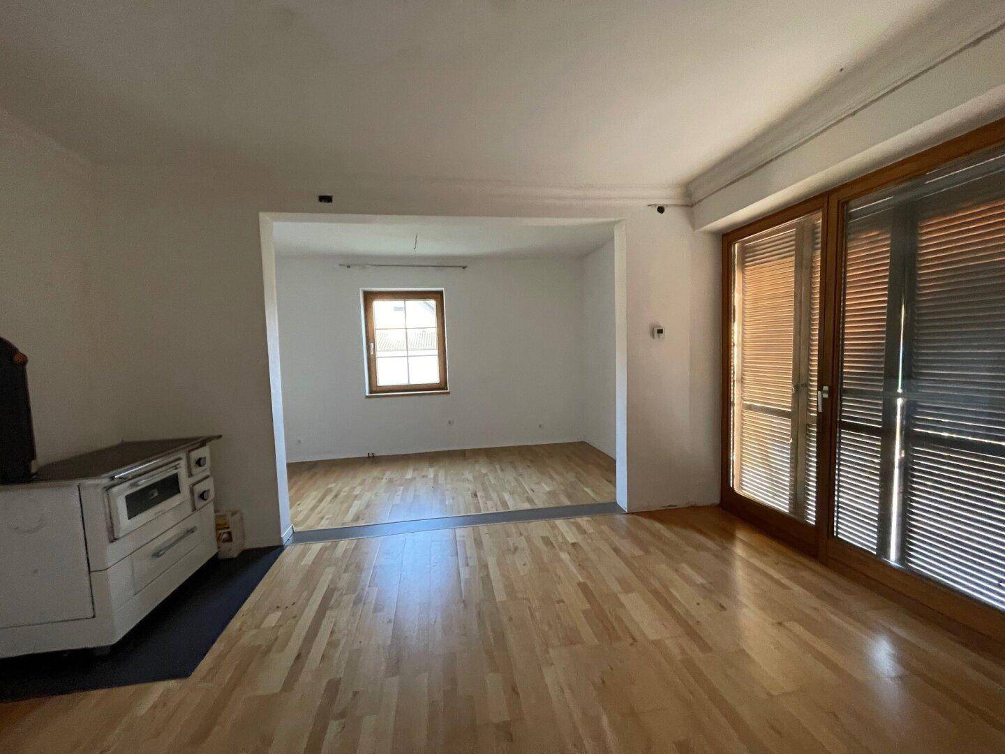 Helles Wohnzimmer mit Holzofen und großen Schiebetüren, die viel Tageslicht hereinlassen.