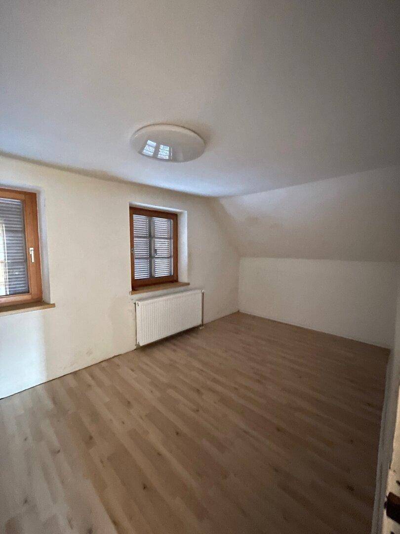 Geräumiges Schlafzimmer im Dachgeschoss mit Laminatboden, zwei Fenstern und Dachschrägen.