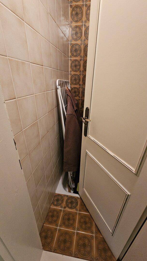 Kleiner Abstellraum mit Fliesenboden und einer Wäschestange, ideal für Haushaltsutensilien.