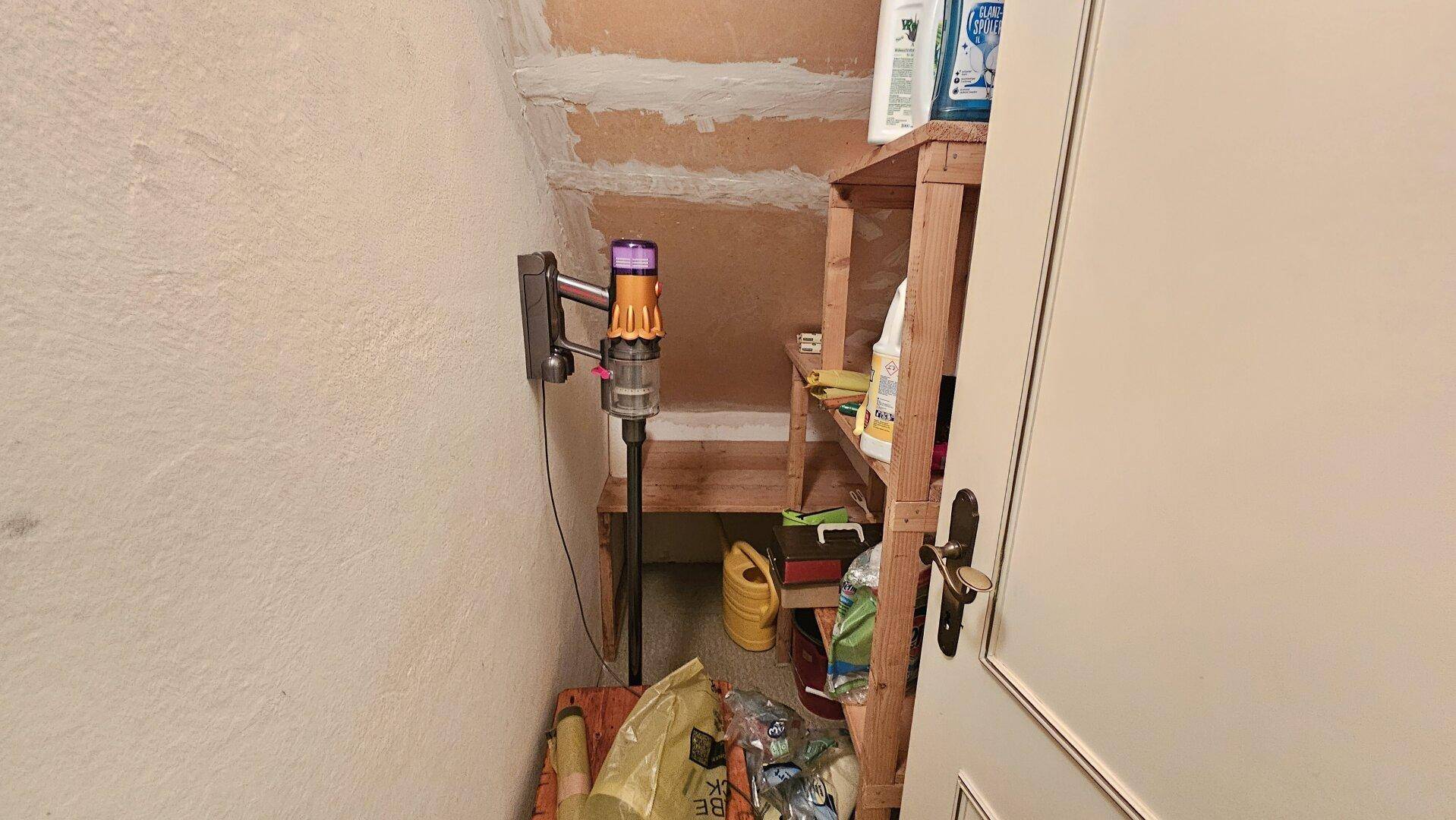 Praktischer Abstellraum unter der Treppe mit Regalen und Reinigungsgeräten für den Haushalt.