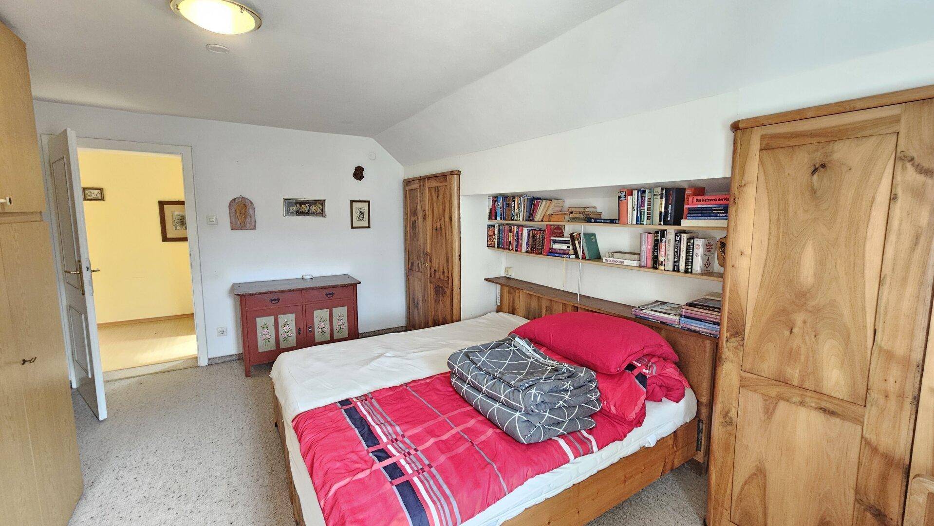 Gemütliches Schlafzimmer mit Teppichboden, Holzbett und eingebauten Regalen für Bücher.