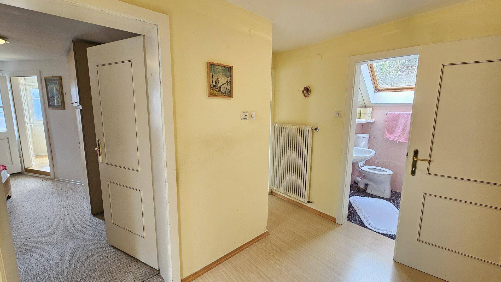 Heller Flur mit Holzboden, der Zugang zu einem Schlafzimmer und einem Badezimmer bietet.