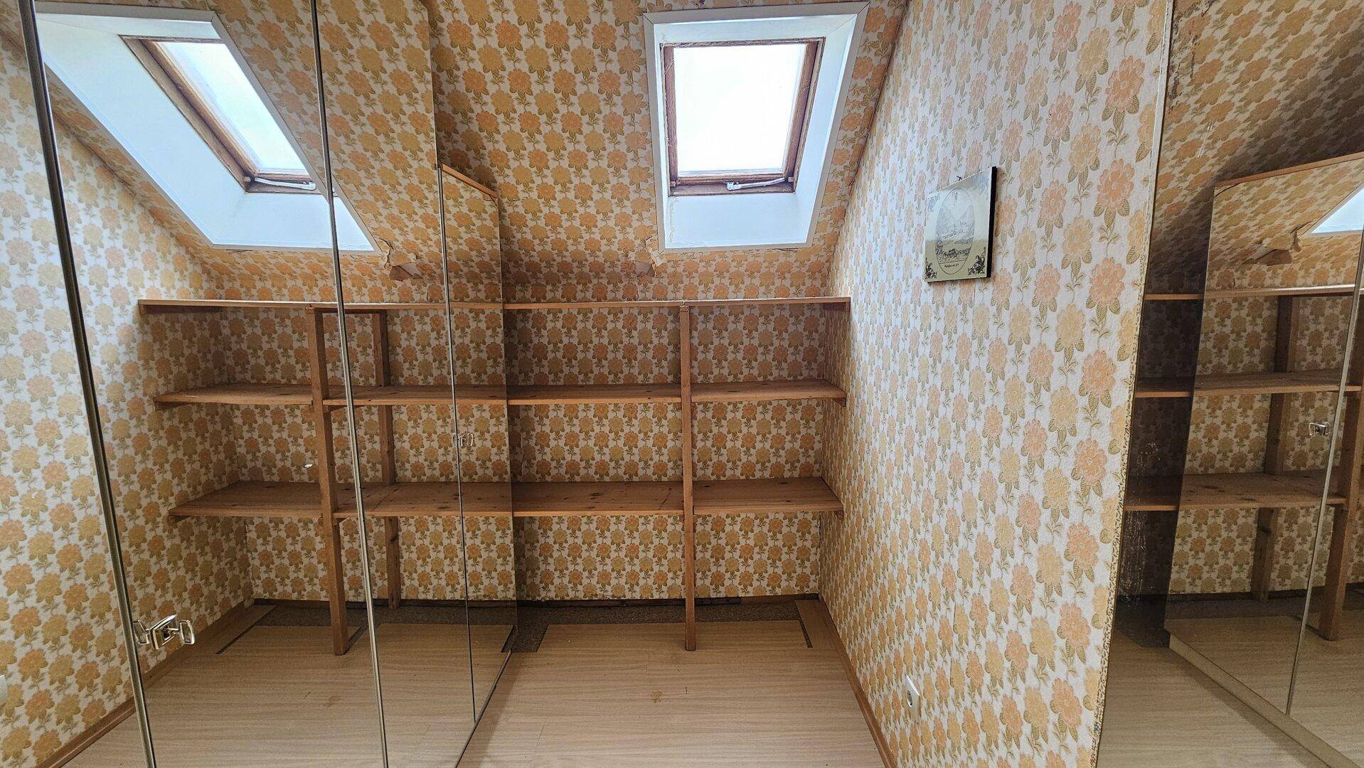 Abstellraum mit Regalen, Spiegelfronten und Dachfenstern, ideal für zusätzlichen Stauraum.