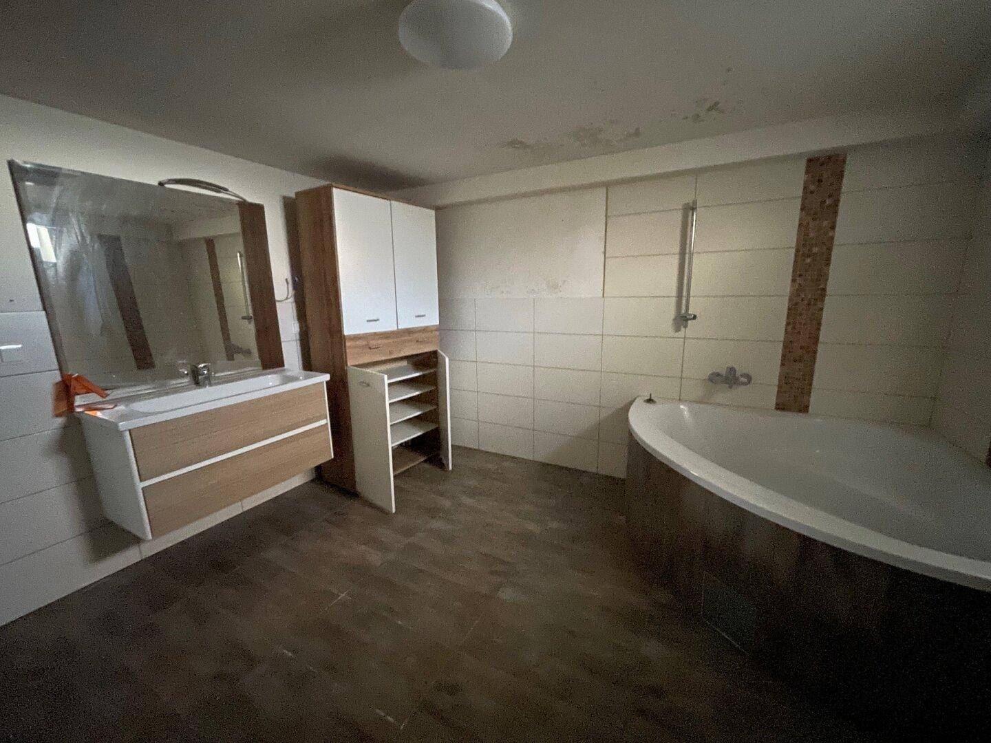 Modernes Badezimmer mit Eckbadewanne, Waschtisch und praktischen Schränken.