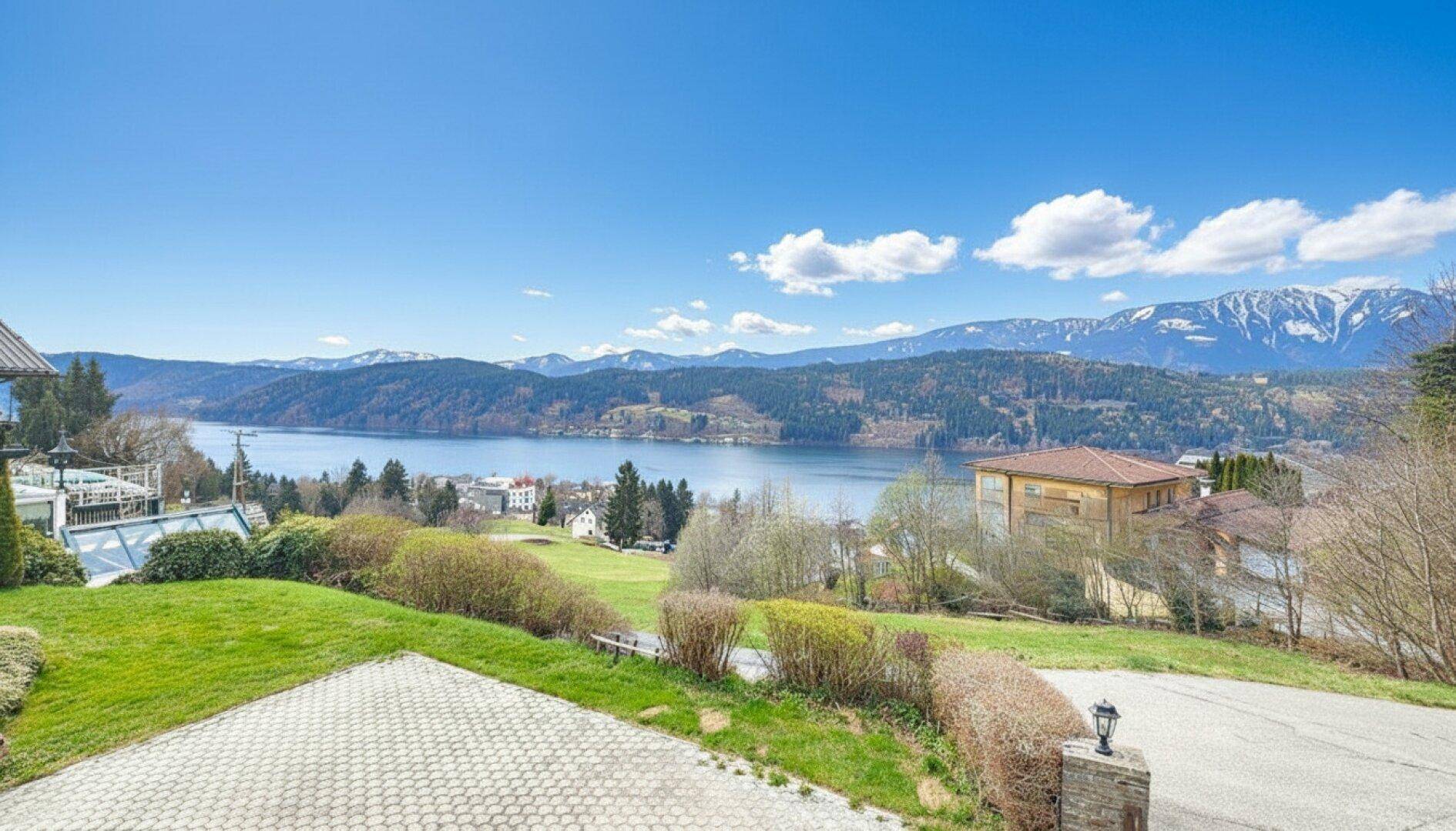 Weitläufiger Blick über einen See und die umliegende Berglandschaft unter einem klaren blauen Himmel.