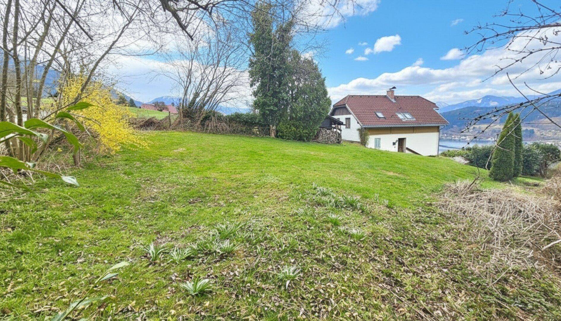 Weitläufiger Rasenbereich des Gartens mit Blick auf das Haus und die umliegende Naturlandschaft.