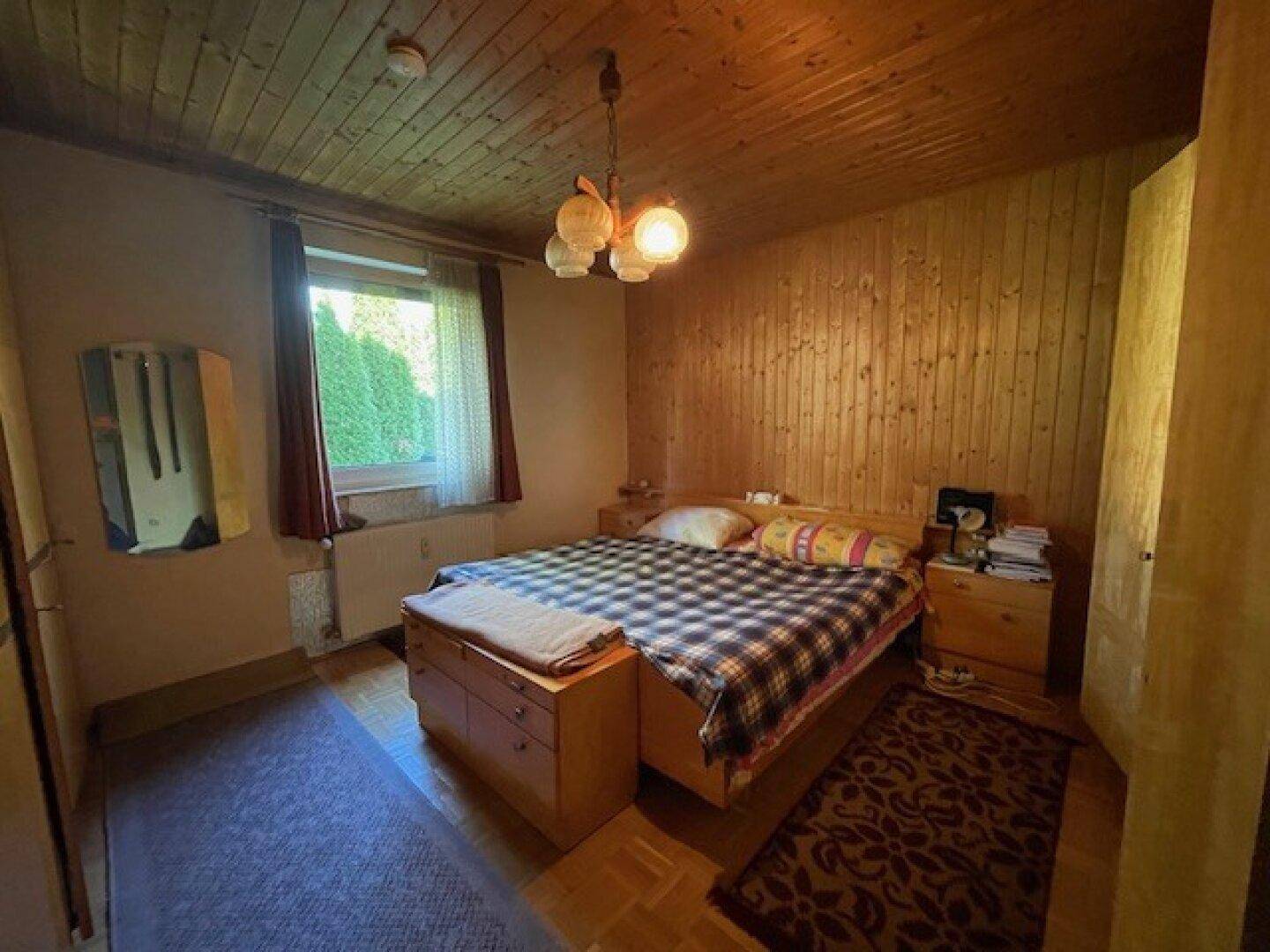 Schlafzimmer mit Holzdecke und Holzwandverkleidung, ausgestattet mit einem Doppelbett und Nachttischen.