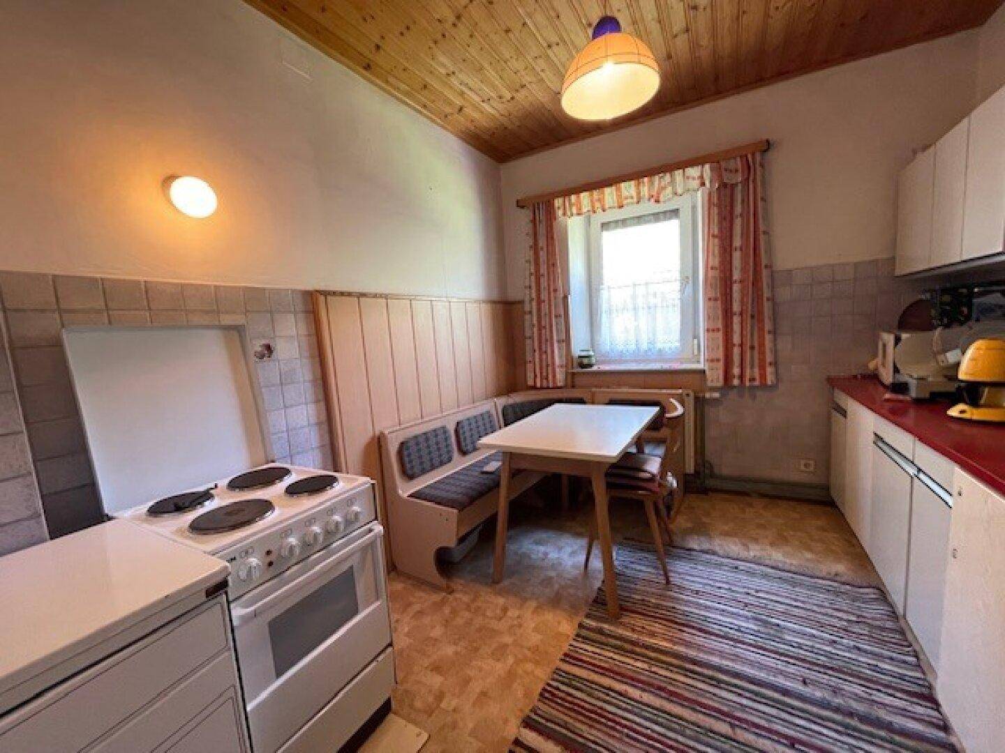 Rustikale Küche mit Essbereich, traditionellem Herd und Holzdecke, ideal für gemütliche Mahlzeiten.