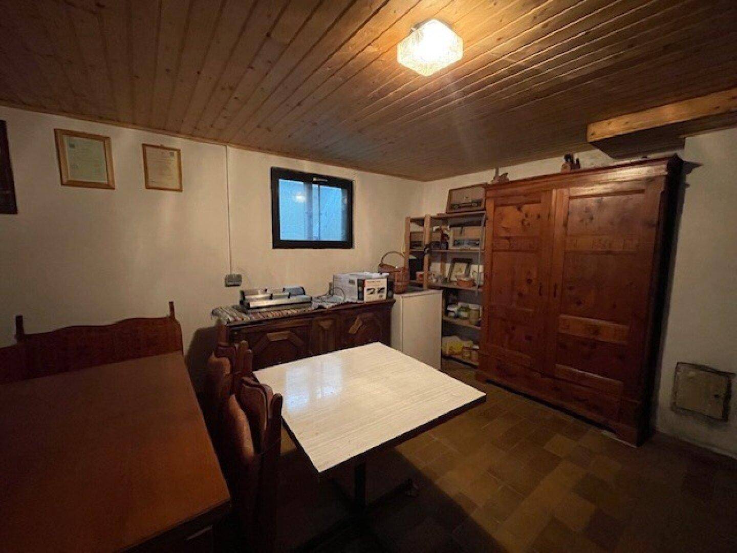 Kellerraum mit Holzdecke, traditionellen Möbeln und einem kleinen Fenster.