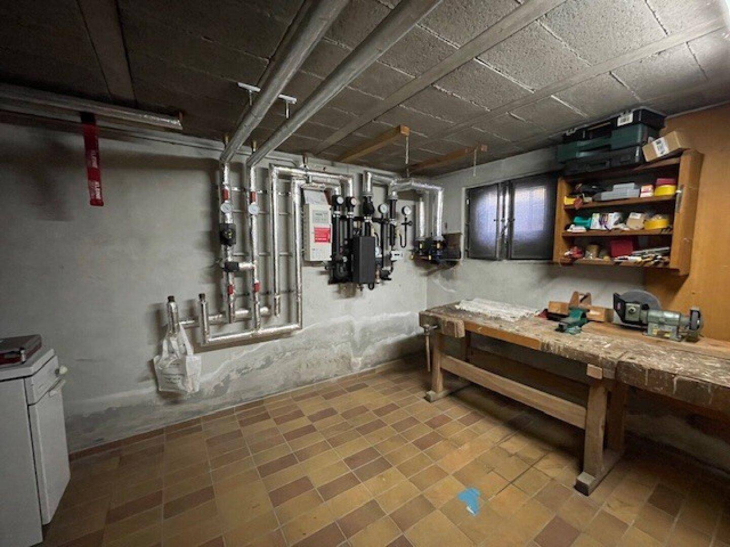 Hauswirtschaftsraum im Keller mit Heizungsinstallationen und einer Werkbank.