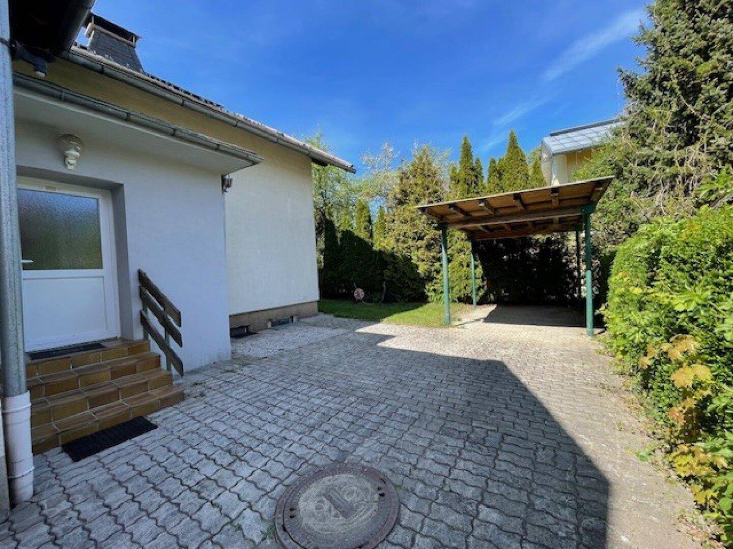 Eingangsbereich des Hauses mit gepflasterter Zufahrt und Blick auf den Carport.