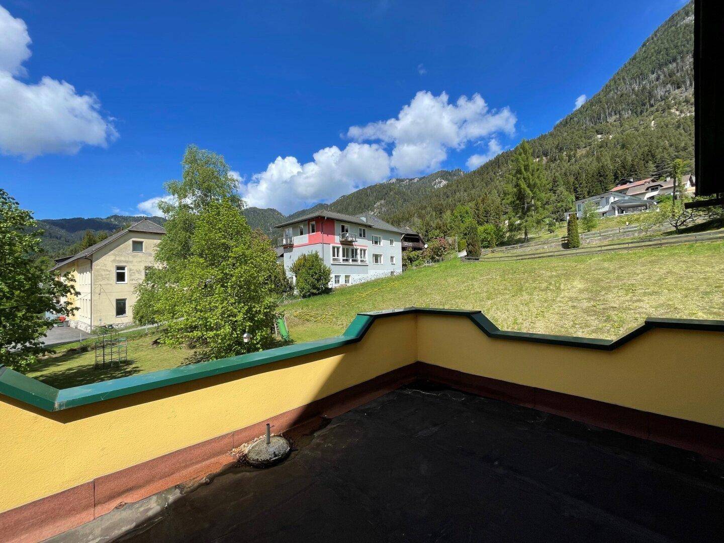 Flachdachbereich mit Blick auf die umliegende Berglandschaft und andere Gebäude.