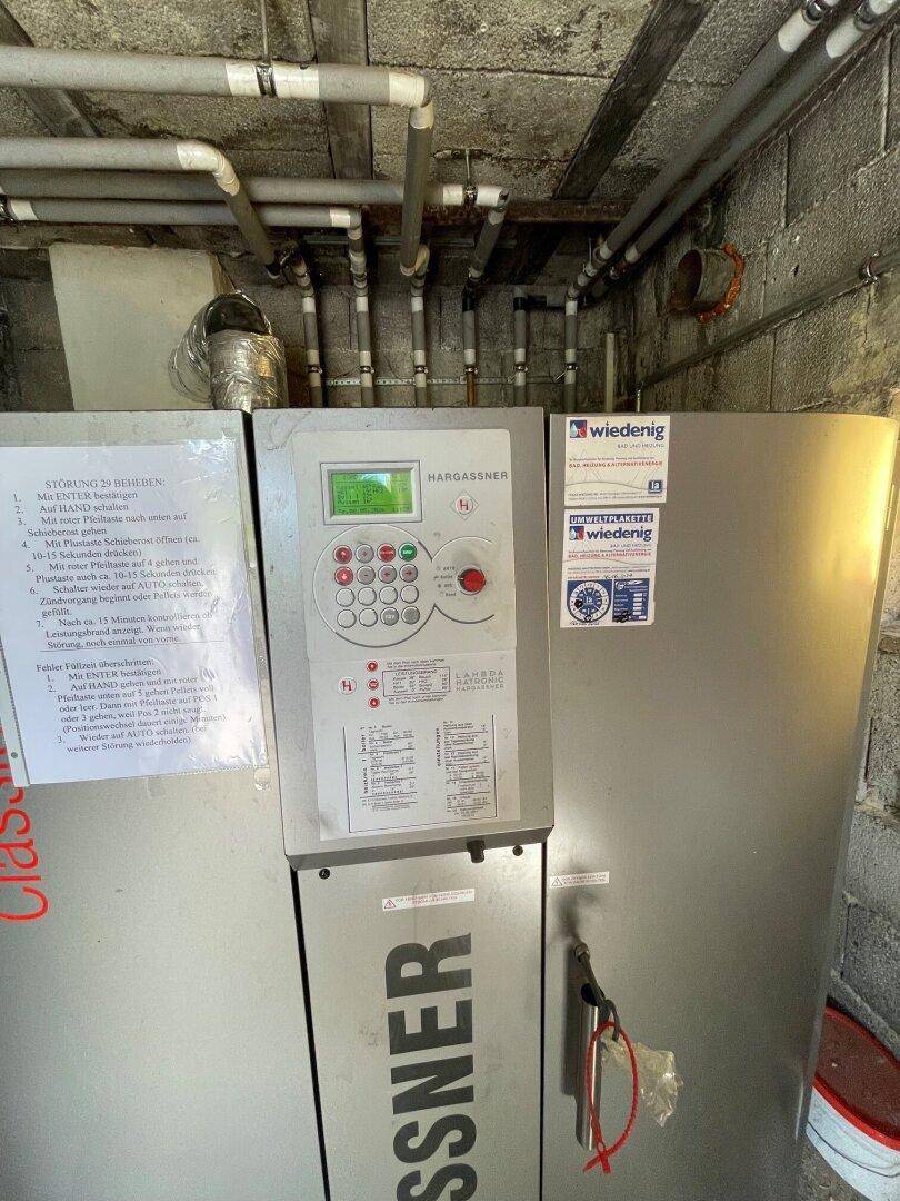 Heizungsraum mit Pelletkessel und Rohrleitungen an der Decke.