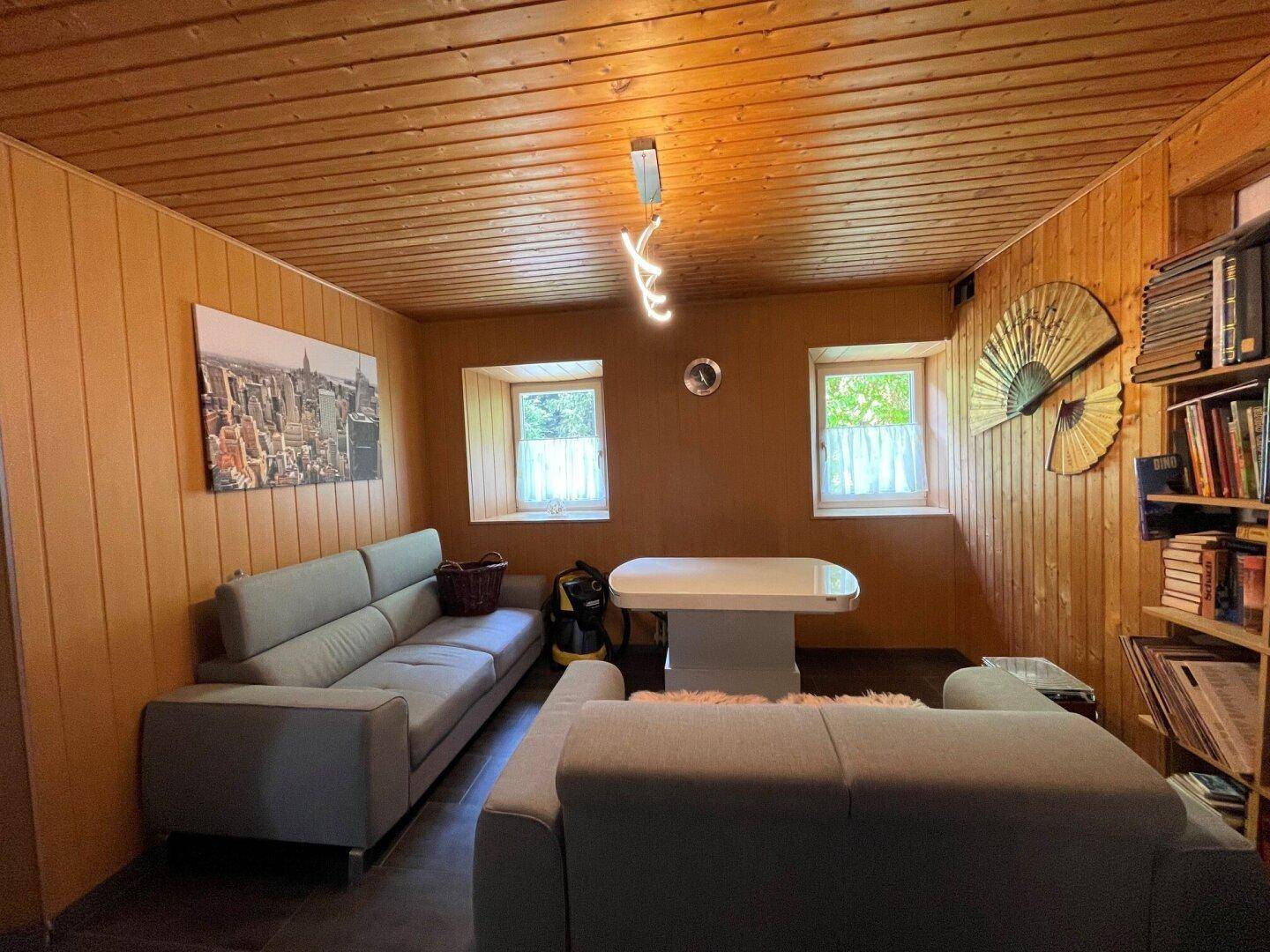 Wohnbereich mit Holzvertäfelung, bequemen Sofas und kleinem Tisch.