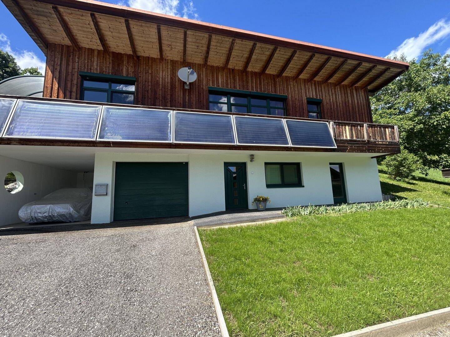 Frontansicht des Hauses mit integrierter Garage, Solarpaneelen und gepflegtem Vorgarten.