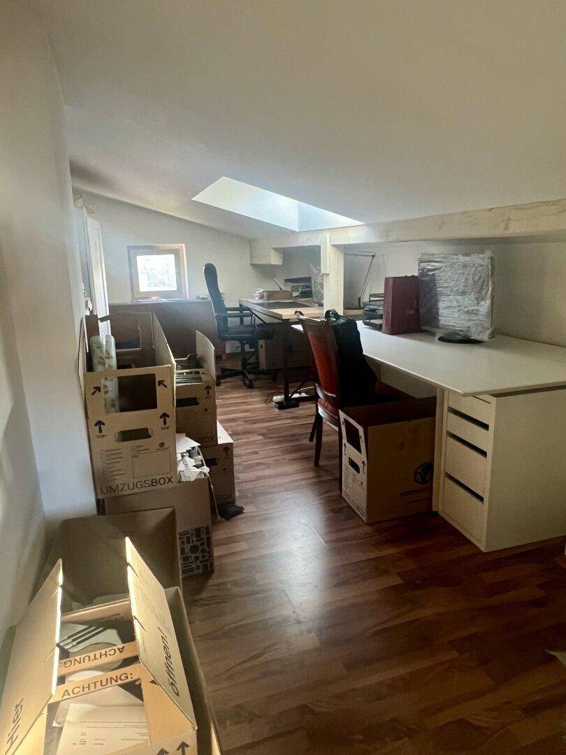 Dachgeschosszimmer als Büro genutzt, mit Dachschräge, Oberlicht und Holzboden, derzeit mit Umzugskartons.