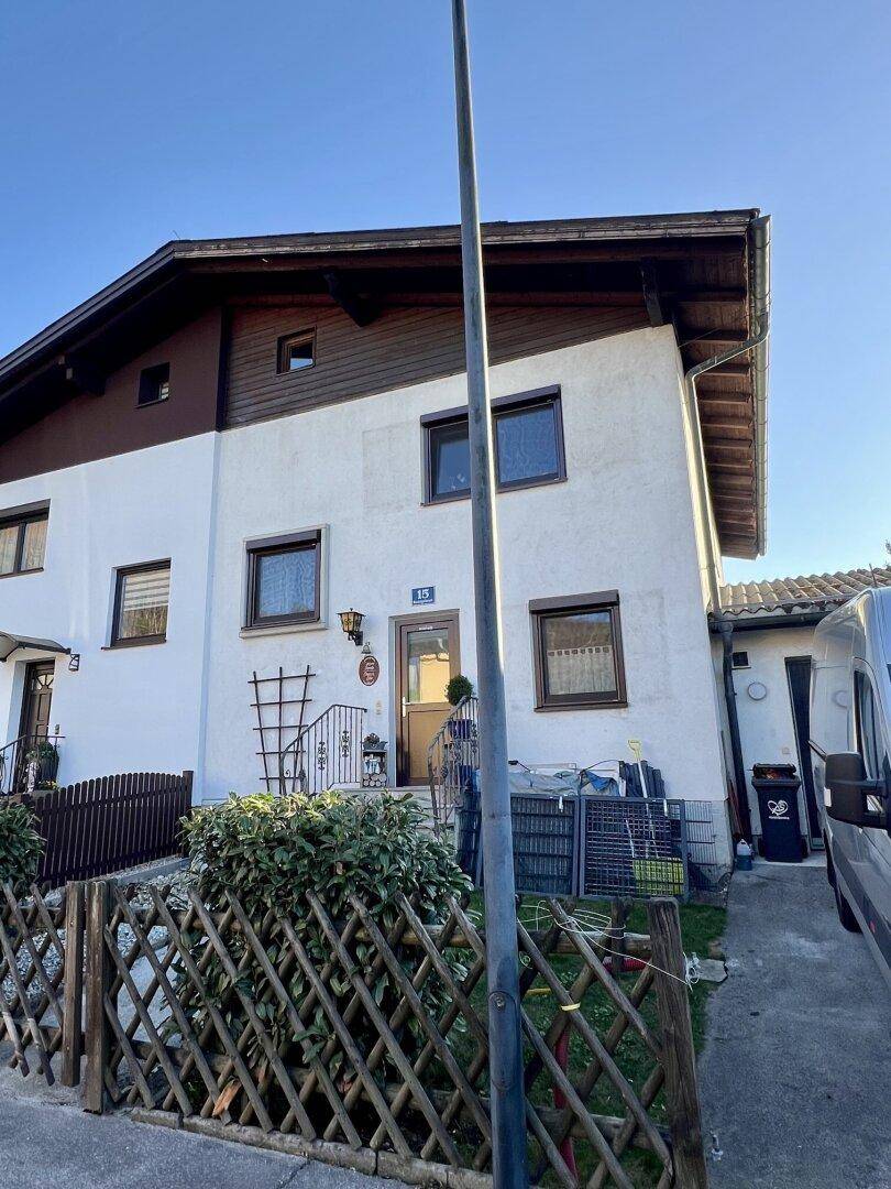 Vorderansicht des Hauses mit Eingangstür, Fenstern und einem kleinen Vorgarten mit Holzzaun.
