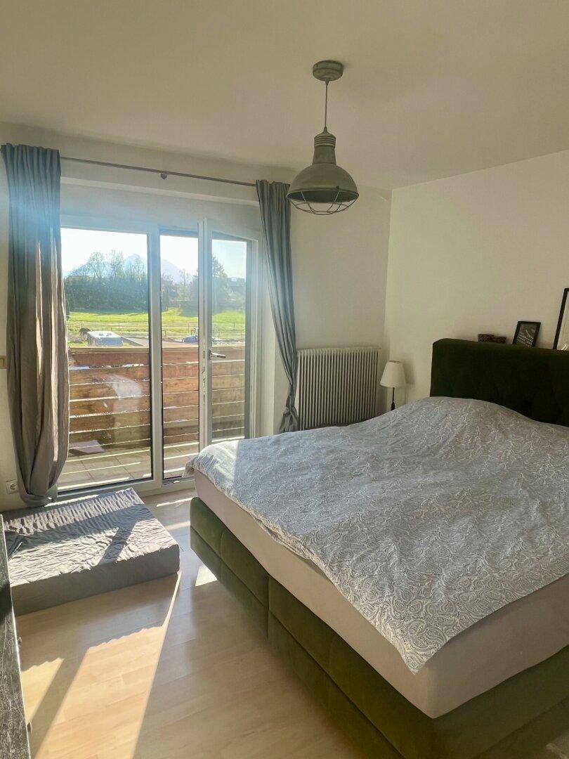 Helles Schlafzimmer mit Doppelbett, hellem Holzboden und direktem Zugang zu einem sonnigen Balkon.