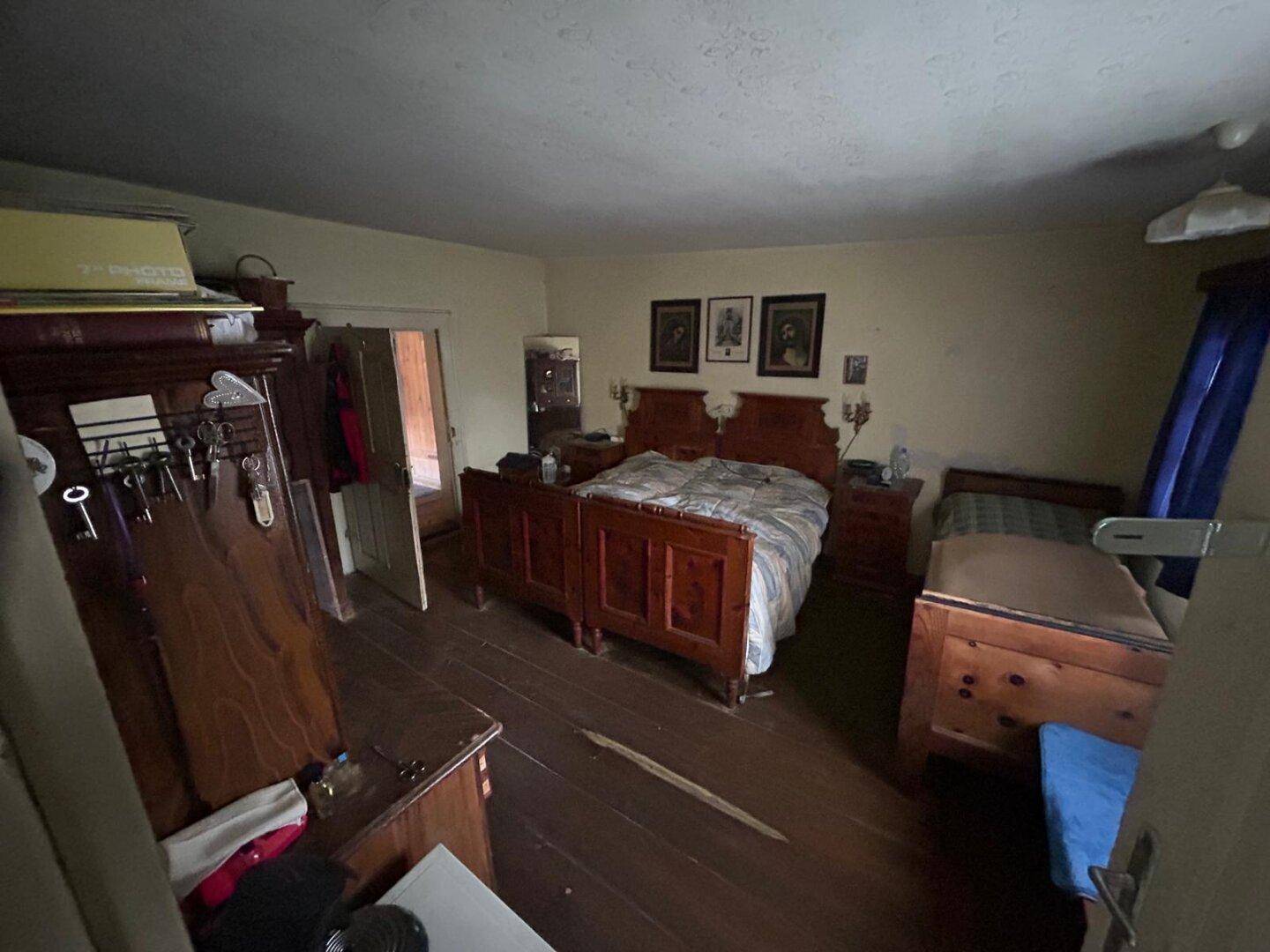 Rustikales Schlafzimmer mit Holzboden, zwei Einzelbetten und traditionellen Holzmöbeln, gemütlich eingerichtet.