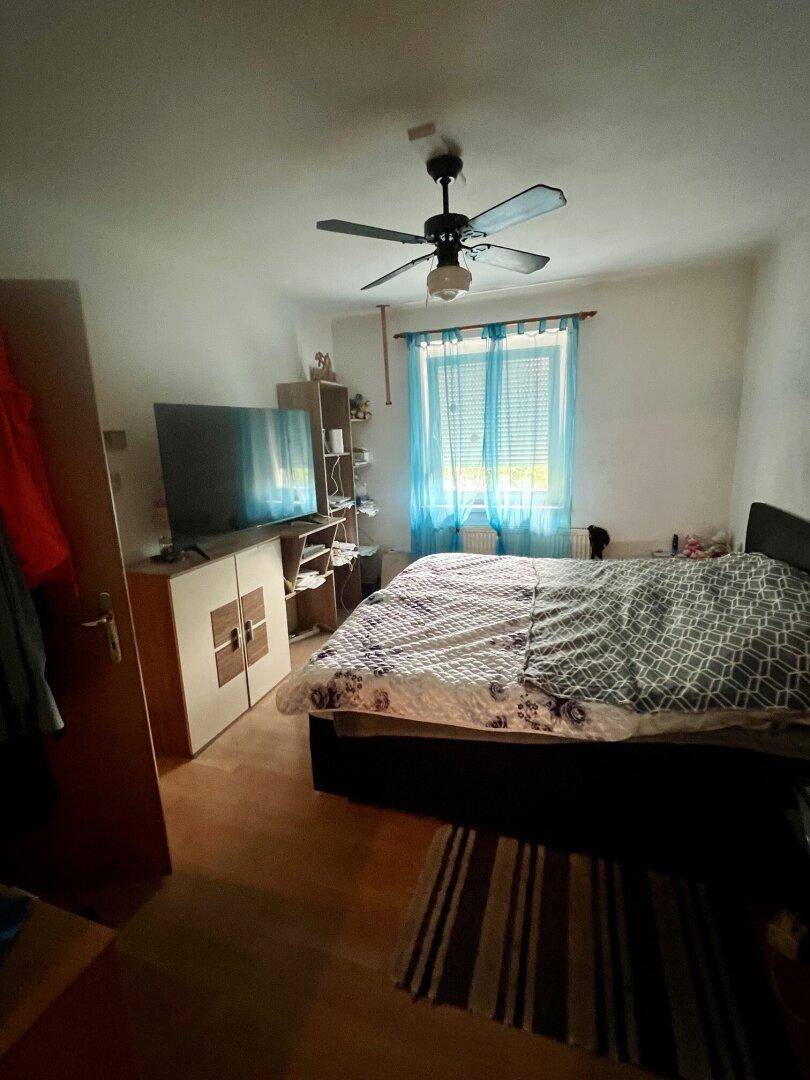 Schlafzimmer mit Doppelbett, Laminatboden und Deckenventilator.