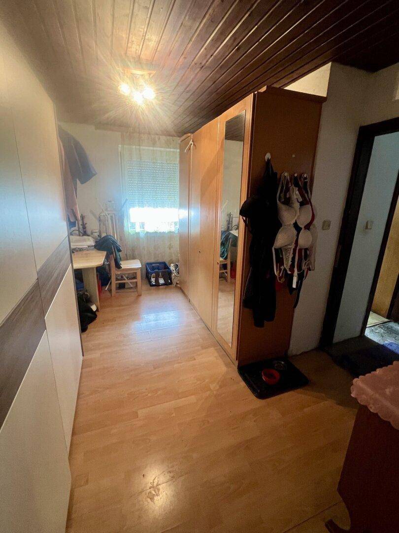 Schlafzimmer mit Laminatboden, Holzdecke und einem großen Kleiderschrank mit Spiegel.
