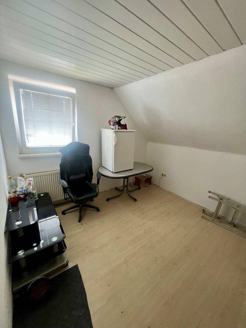 Dachgeschosszimmer mit Laminatboden, schrägen Wänden und einem Fenster.