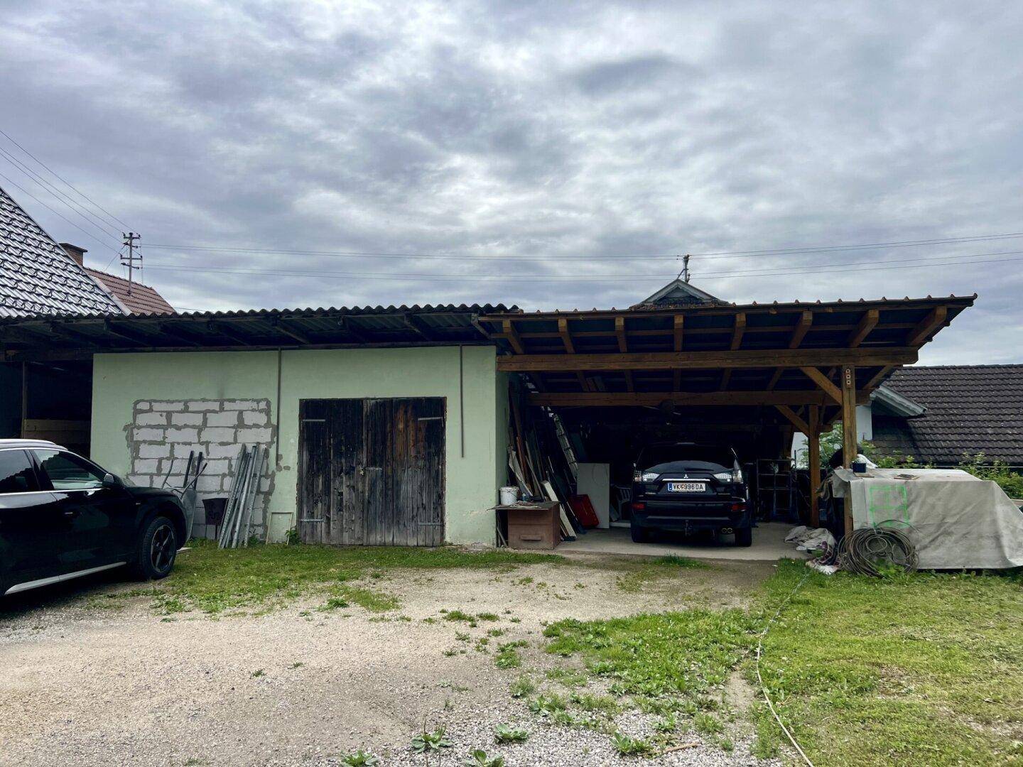 Carport und Schuppen neben dem Haus mit einem geparkten Auto.