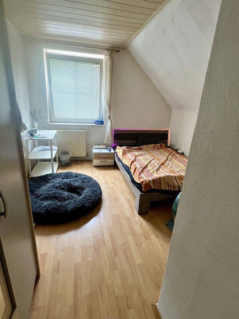 Kleines Schlafzimmer im Dachgeschoss mit Laminatboden und einem Fenster.