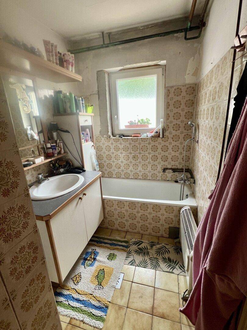 Badezimmer mit Badewanne, Waschbecken und Fliesen im 80er-Jahre-Stil.