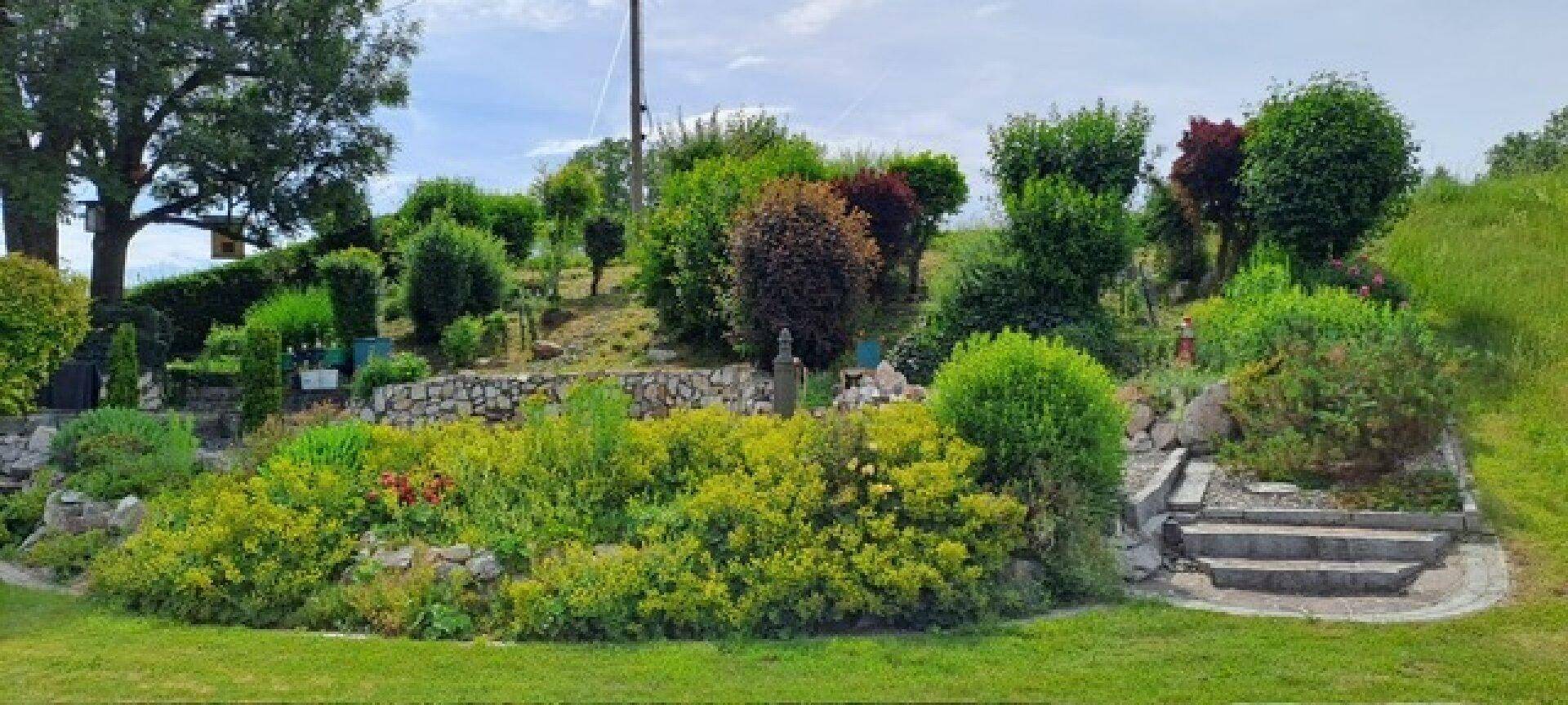 Gestufter Gartenbereich mit vielfältiger Bepflanzung, Steinmauern und Treppen in der Natur.