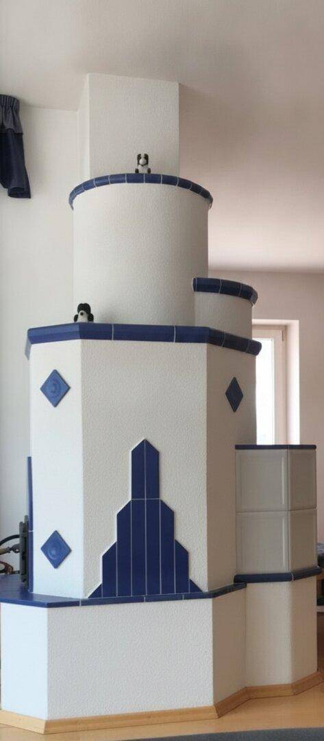 Detailansicht eines traditionellen, weiß-blauen Kachelofens im Wohnbereich.