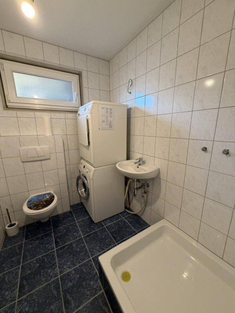 Praktischer Hauswirtschaftsraum mit Waschmaschine, Trockner, WC und Duschwanne.
