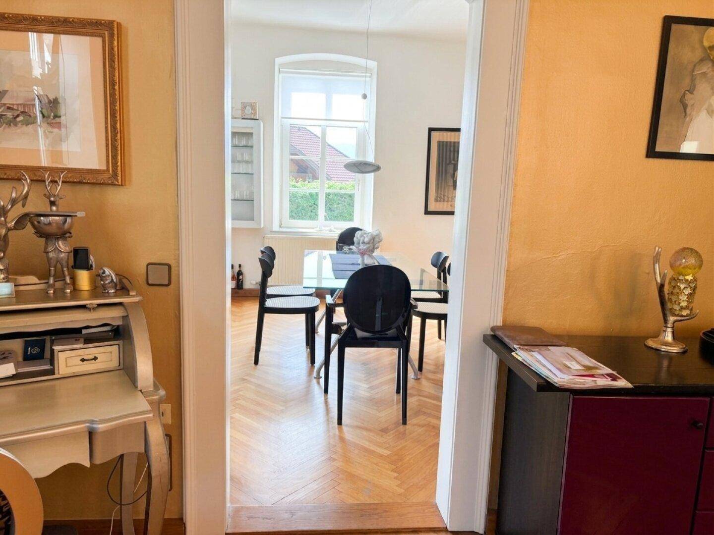 Blick vom Wohnbereich in das Esszimmer durch einen eleganten Torbogen, mit viel Tageslicht.