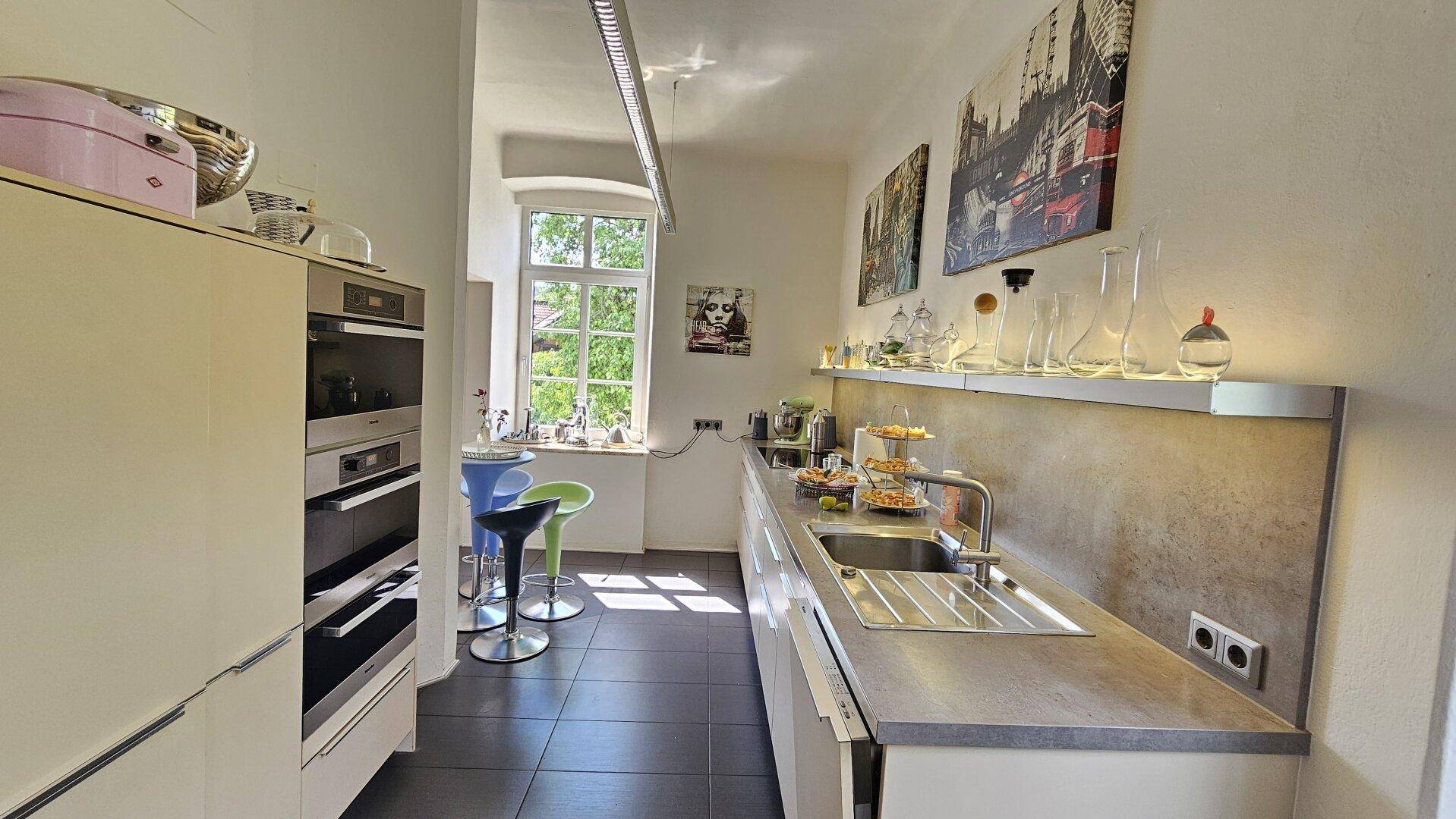 Funktionale Küche mit viel Arbeitsfläche, Fenster und Barhockern, ideal für schnelles Frühstück.