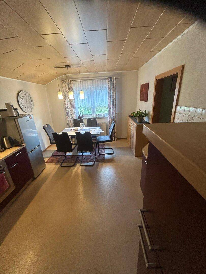 Helle Küche mit Essbereich, Kühlschrank und Holzdecke.