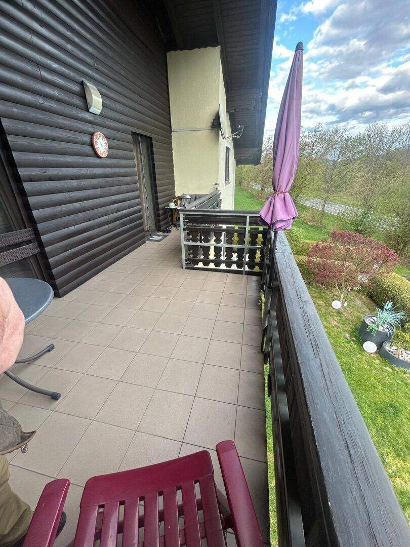 Gefliester Balkon mit Holzbalkonbrüstung und Blick ins Grüne.
