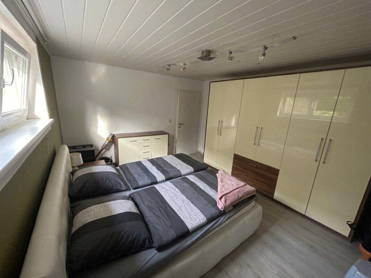 Helles Schlafzimmer mit Doppelbett und geräumigen weißen Kleiderschränken.