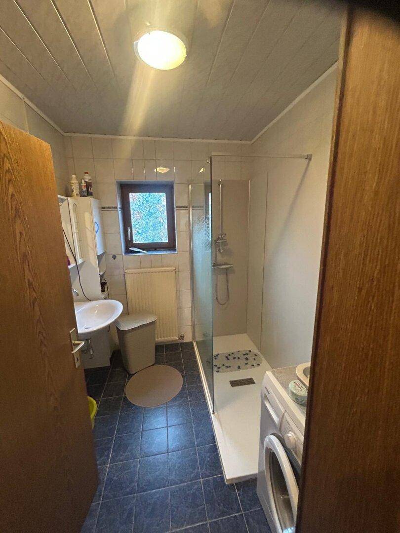 Badezimmer mit Dusche, Waschbecken und Toilette.
