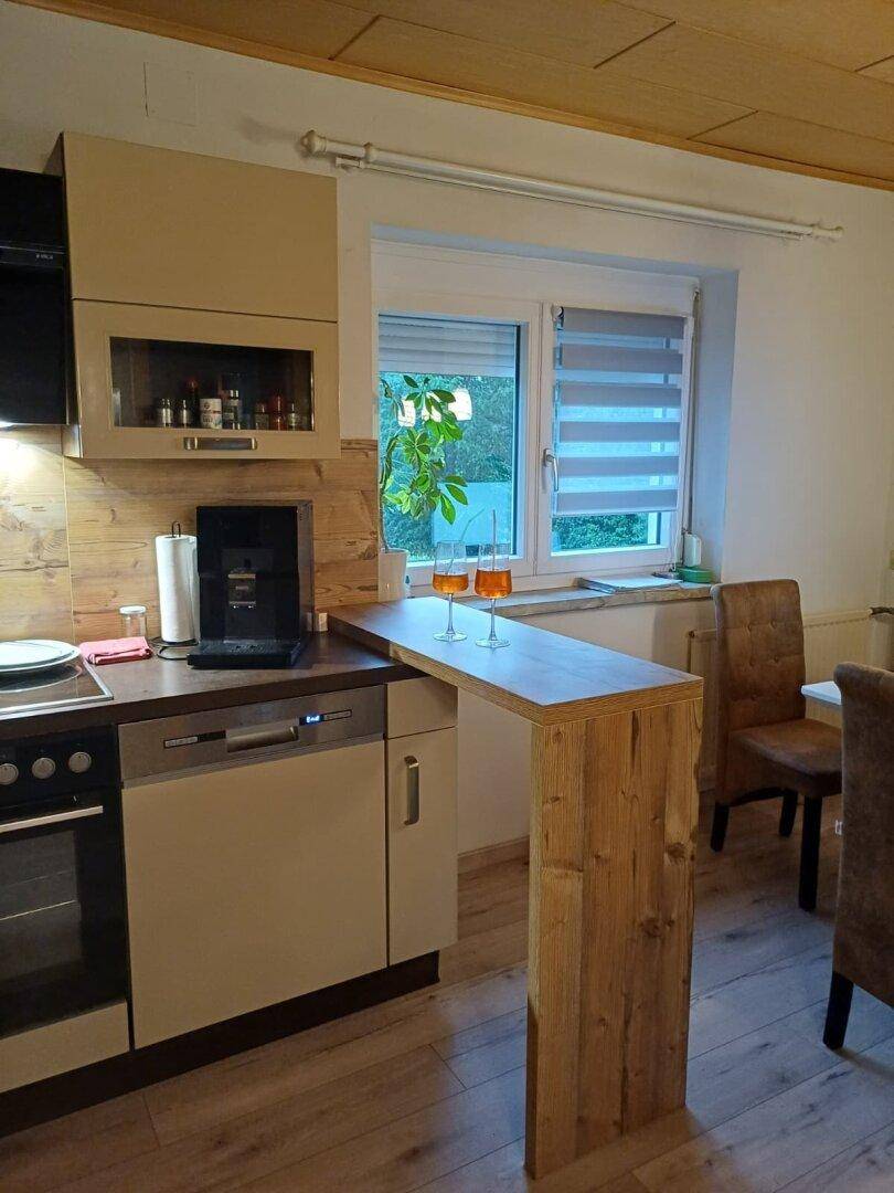 Moderne Küche mit integriertem Geschirrspüler und Frühstücksbar aus Holz.