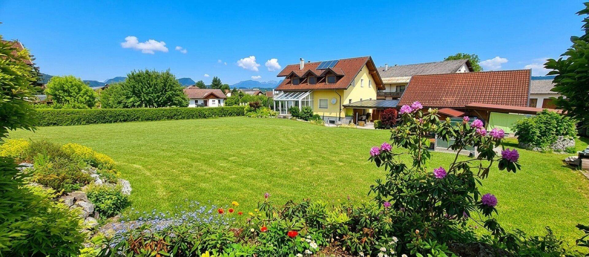 Großer, gepflegter Garten mit weitläufiger Rasenfläche und blühenden Sträuchern vor dem Haus.