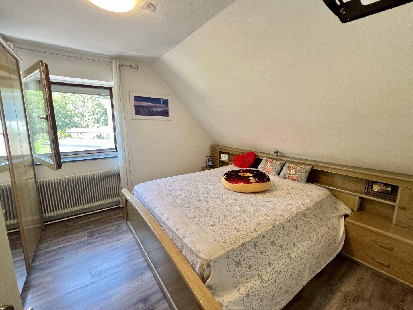 Helles Schlafzimmer mit Holzbett, integrierten Nachttischen und Blick ins Grüne.