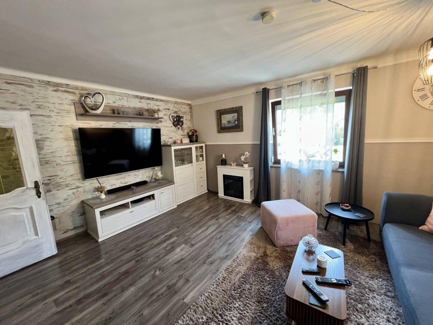 Helles Wohnzimmer mit TV-Möbeln, Kamin und dekorativer Wandgestaltung.