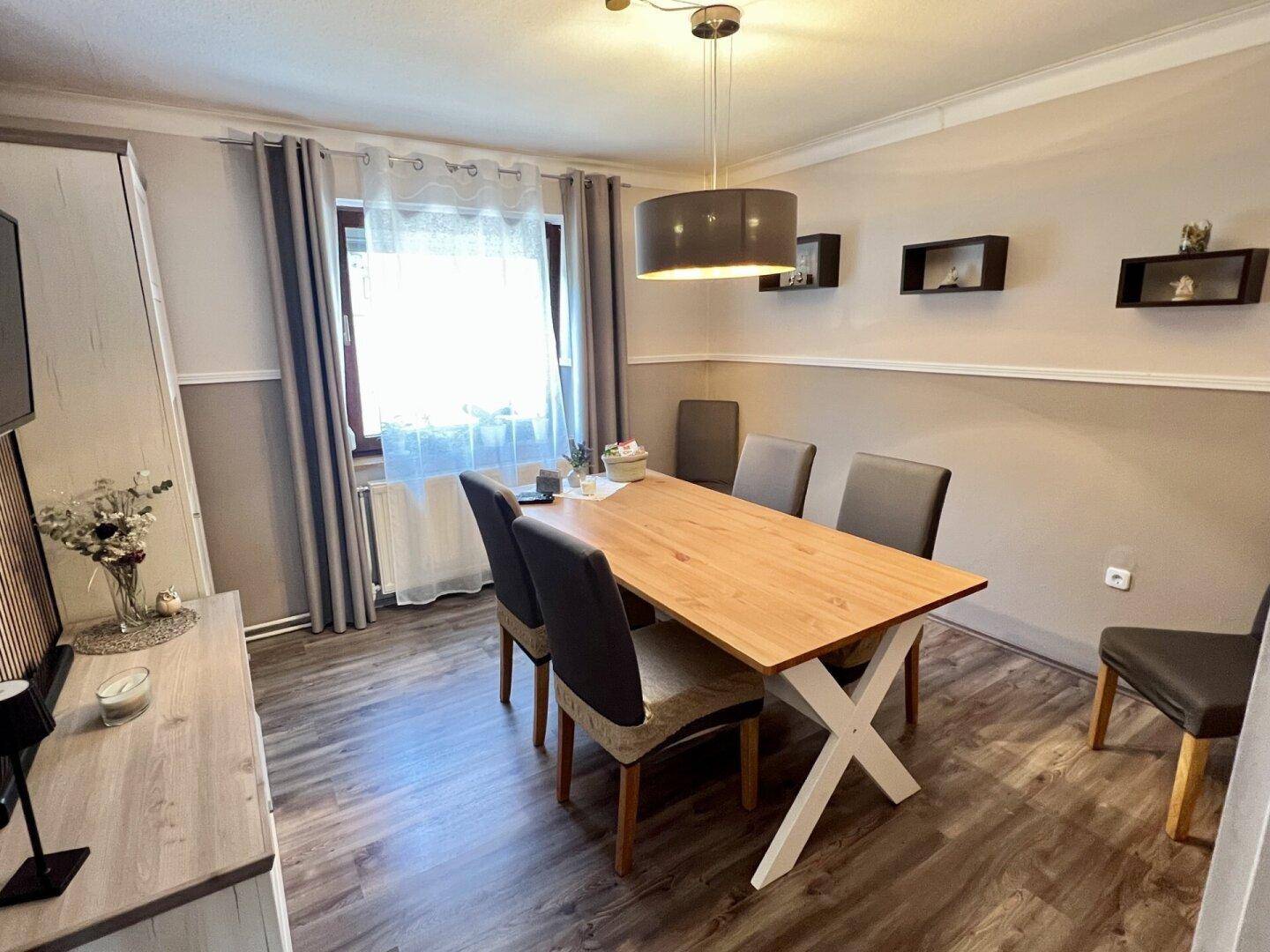 Heller Essbereich mit Holztisch, modernen Stühlen und Laminatboden.