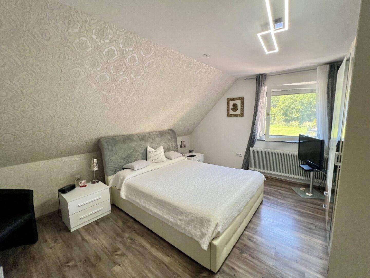 Schlafzimmer im Dachgeschoss mit Doppelbett, Nachttischen und schräger Decke.