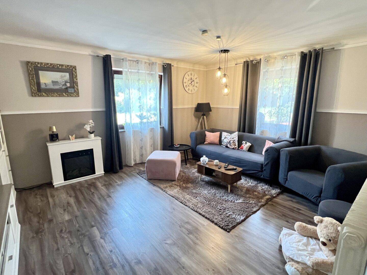 Gemütliches Wohnzimmer mit modernem Laminatboden, Kamin und bequemen Sofas.