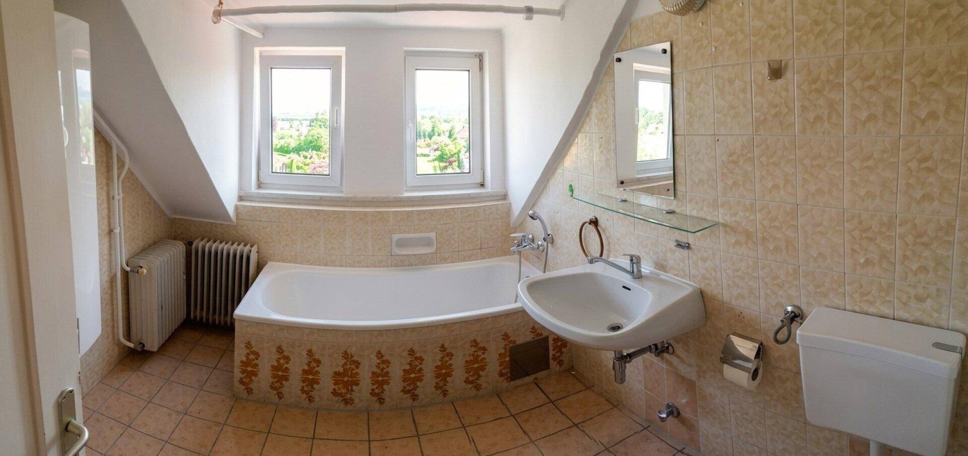 Badezimmer im Dachgeschoss mit Badewanne, Waschbecken und schrägen Wänden.